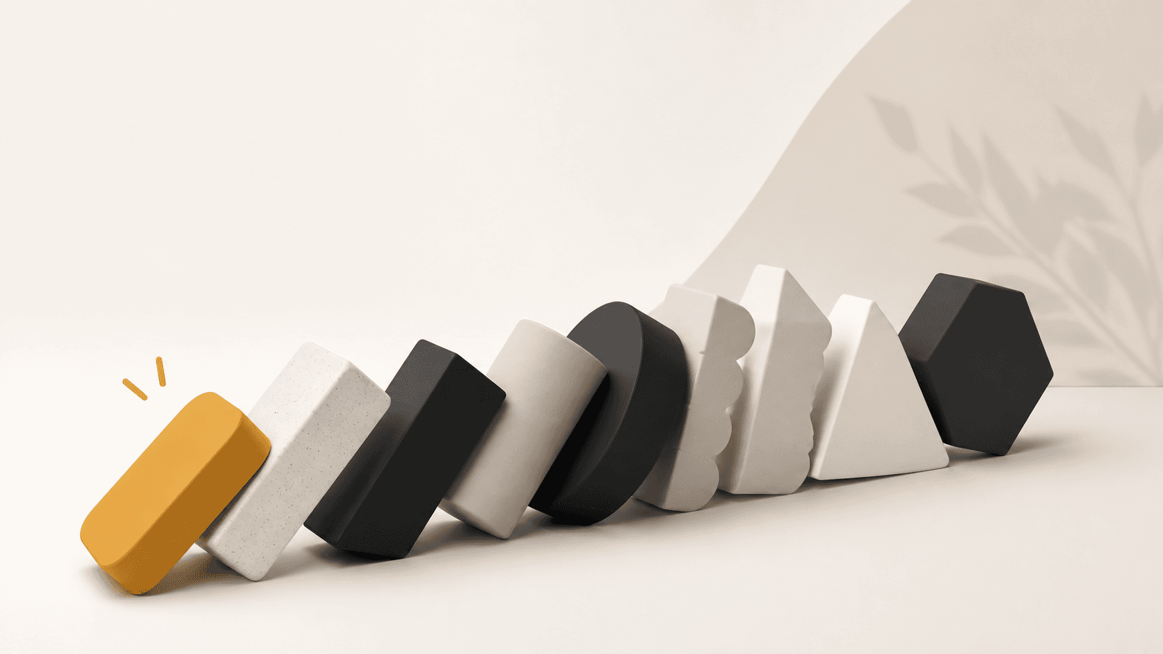 A row of matte shapes toppling like dominoes, from a mustard block through white, black and grey forms to a black hexagon.
